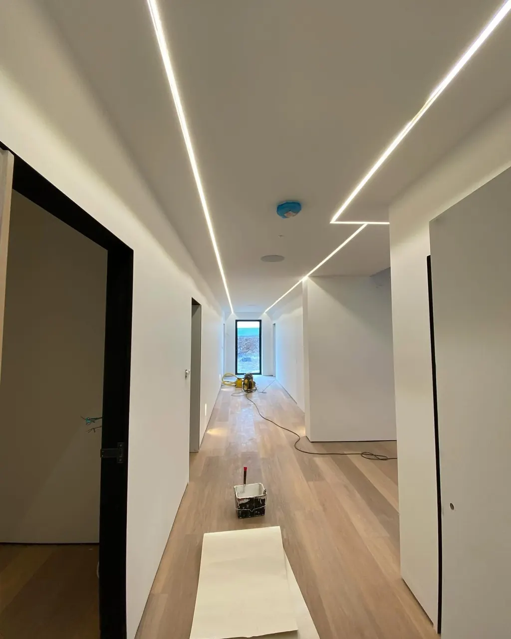 Airless paint sprayer set up in a hallway during interior spraying