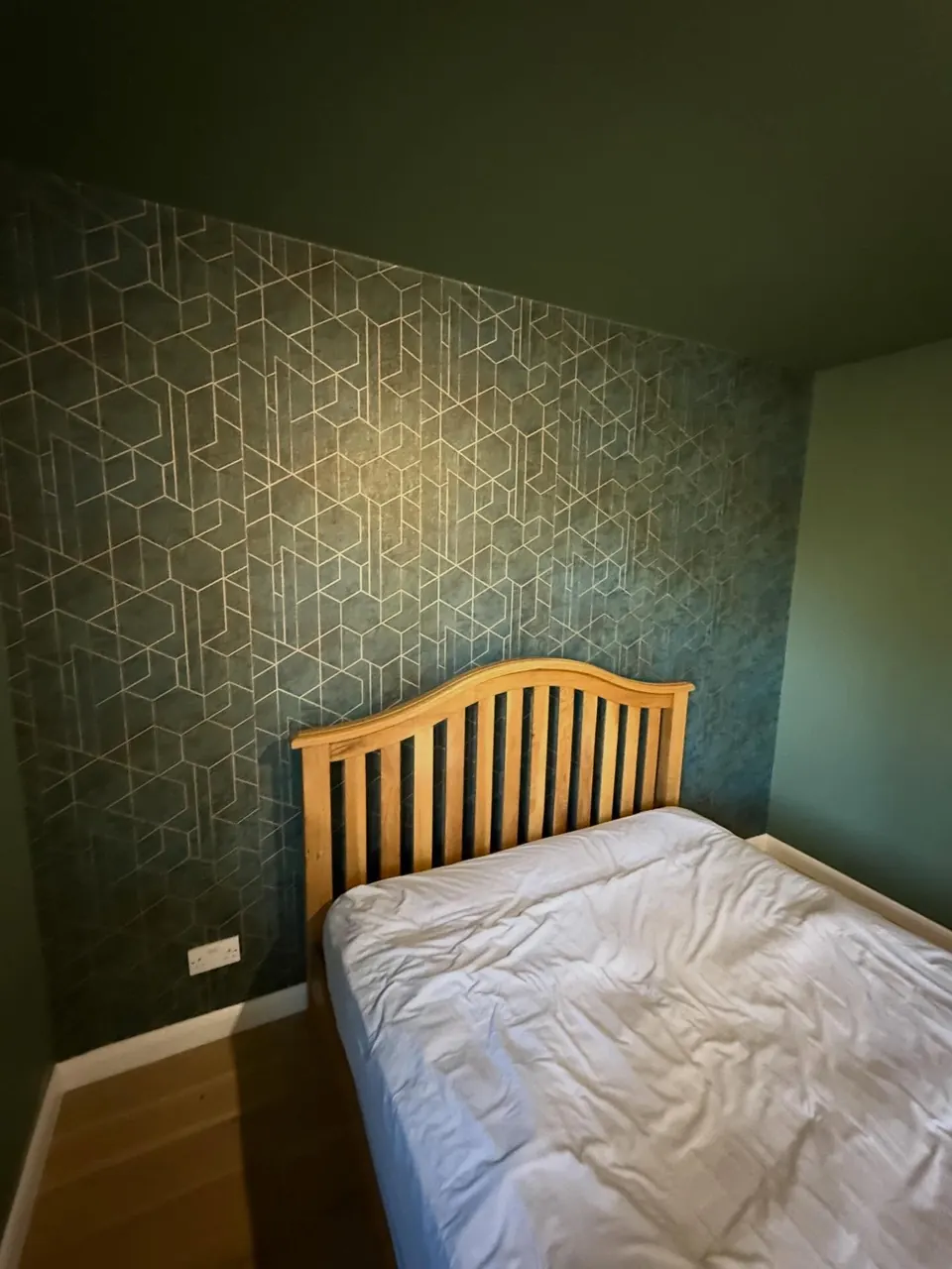 Geometric teal wallpaper feature wall in a bedroom