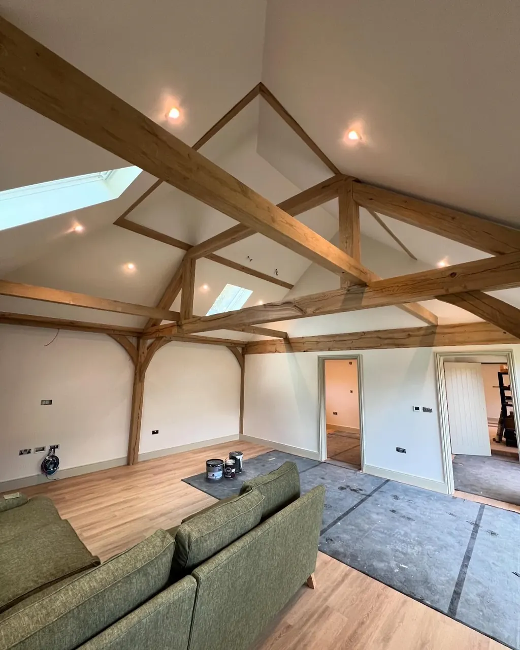 Vaulted room with oak beams during interior painting, floors protected