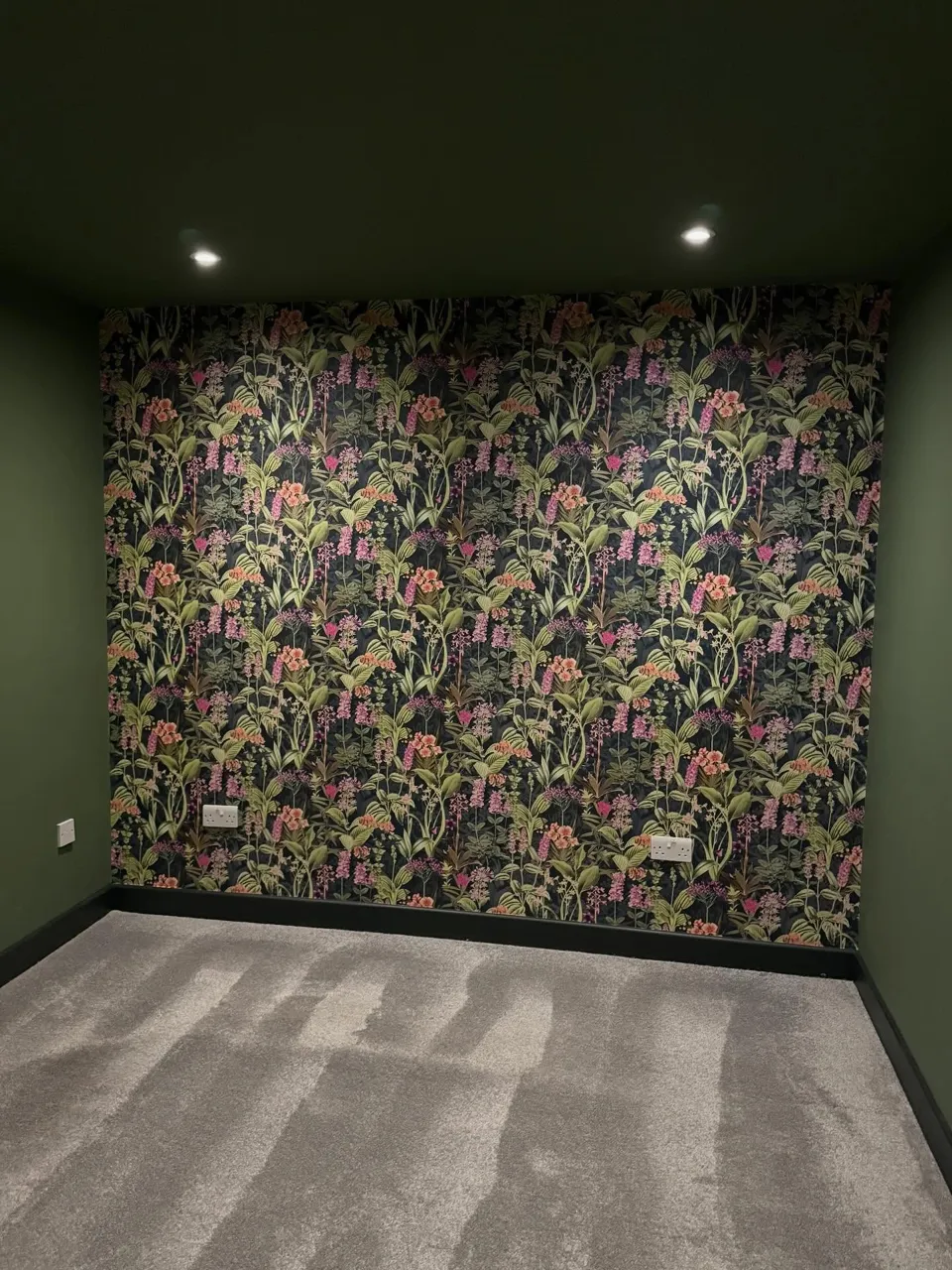 Prepared wall finished with botanical wallpaper in a dark green room
