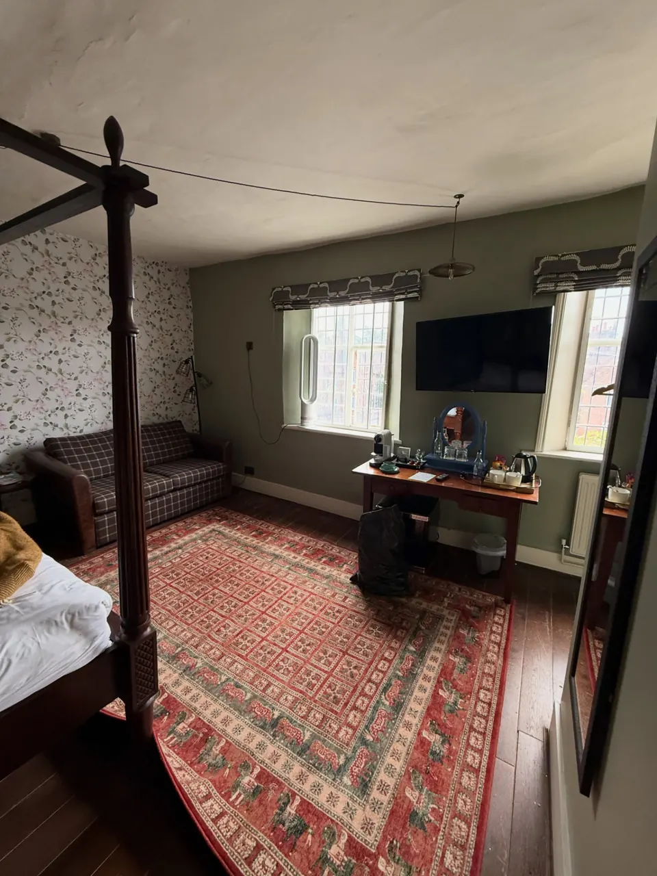 Four-poster guest bedroom with wallpaper and green walls