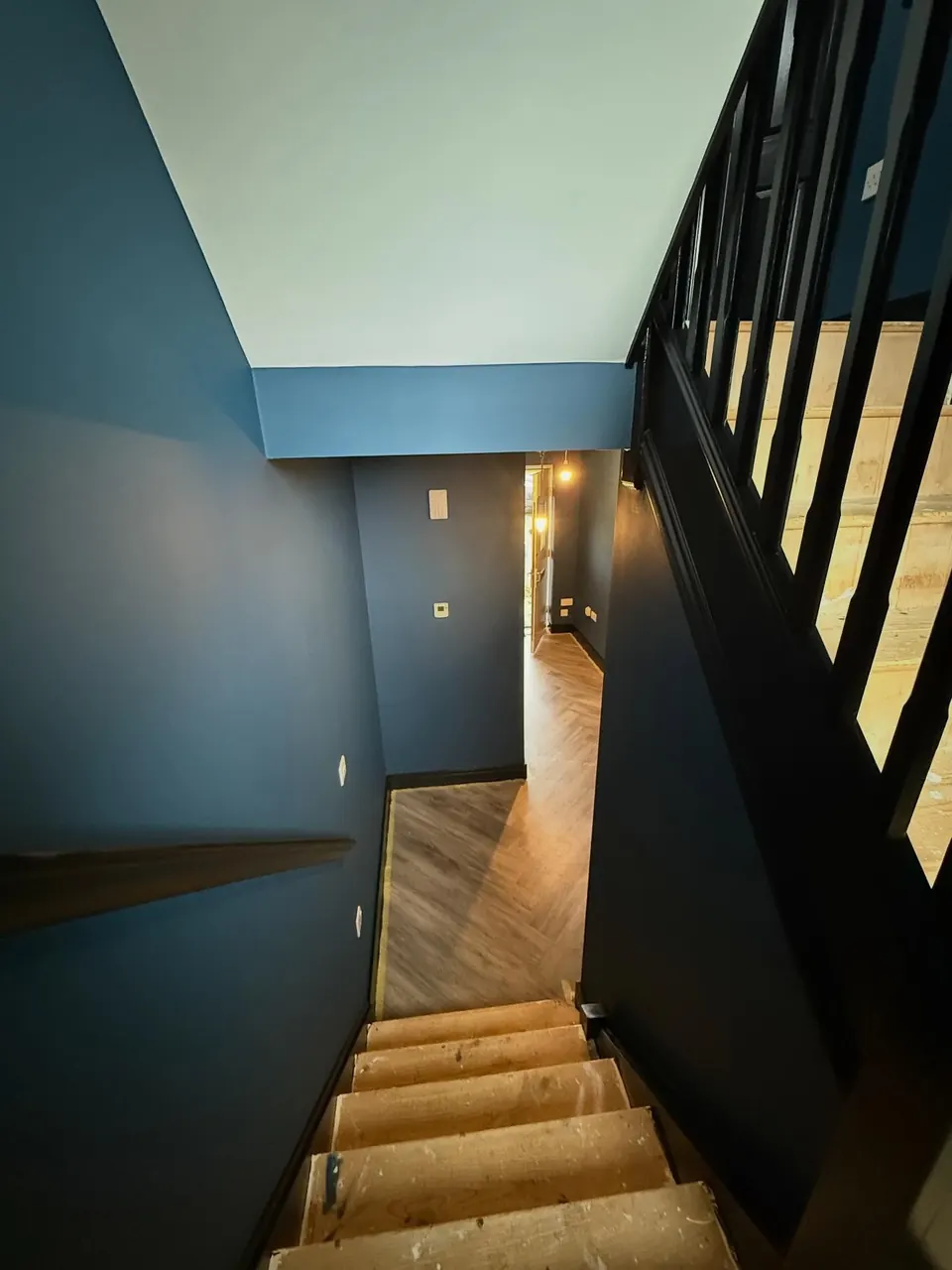 Blue staircase and landing with black railings being decorated