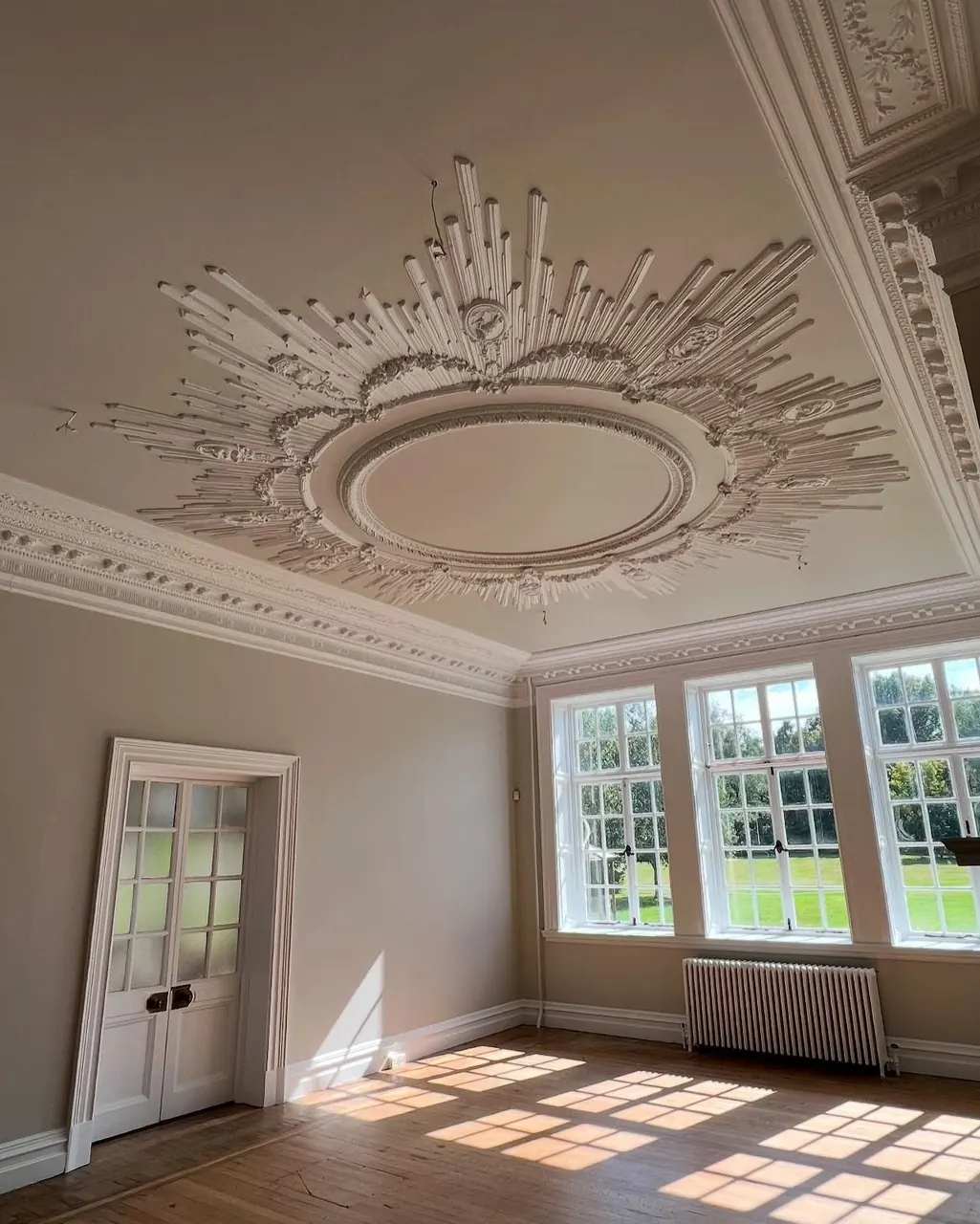 Ornate ceiling and tall windows in a freshly painted period room