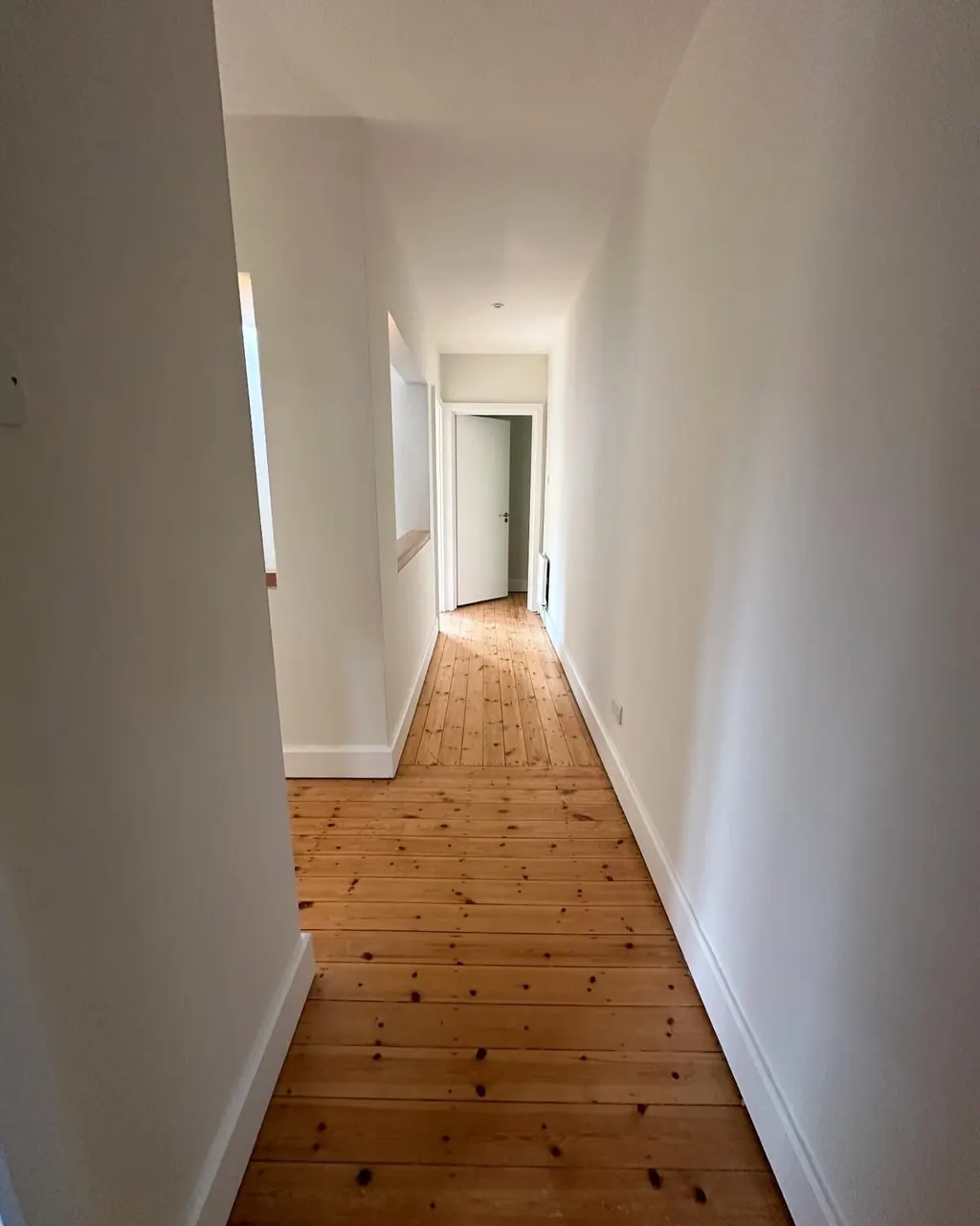Freshly painted white hallway with exposed wooden floorboards